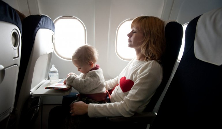Mãe com bebê no colo em viagem de avião