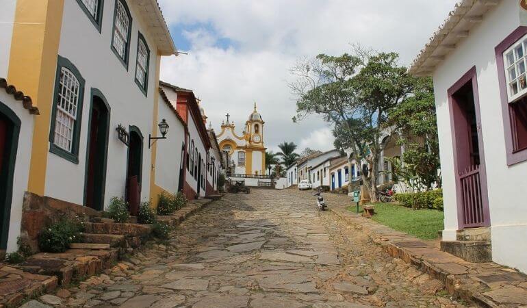 imagem de uma rua de pedras com casas históricas e, ao fundo, a igreja, em Tiradentes/MG