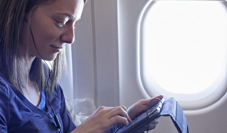 Turista distrai com tablet em voo de avião
