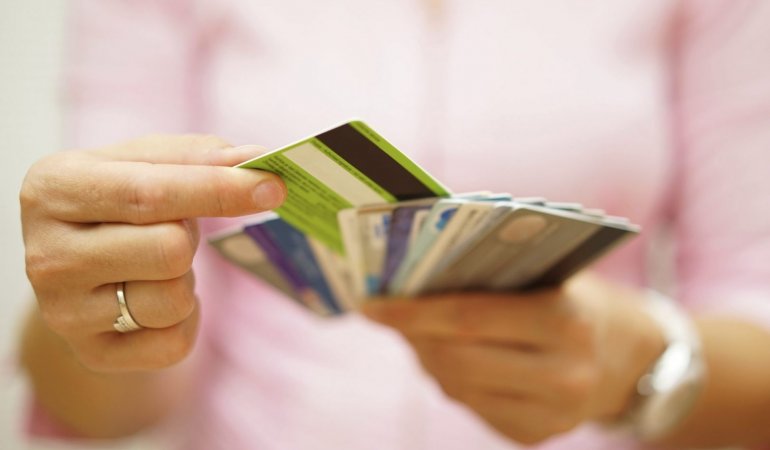 Mulher segura diversos cartões de crédito com milhas