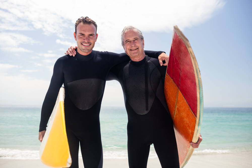 Pai e filho tiram foto com roupas e prancha de surf