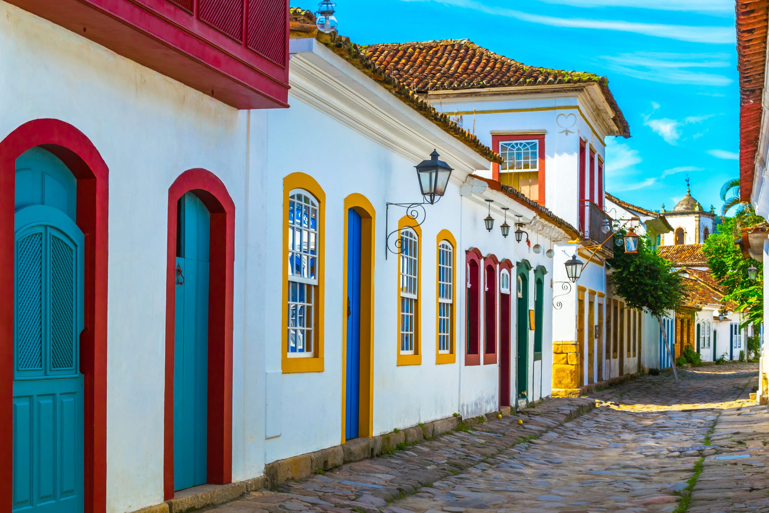 Casas brancas com portas e janelas coloridas, em Paraty. Imagem disponível em Shutterstock.