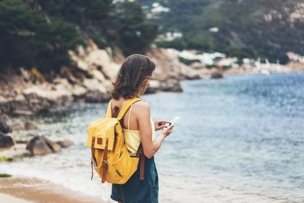 Turista navega no celular em praia paradisíaca