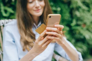 mulher com celular e cartão de crédito vendo como ganhar milhas