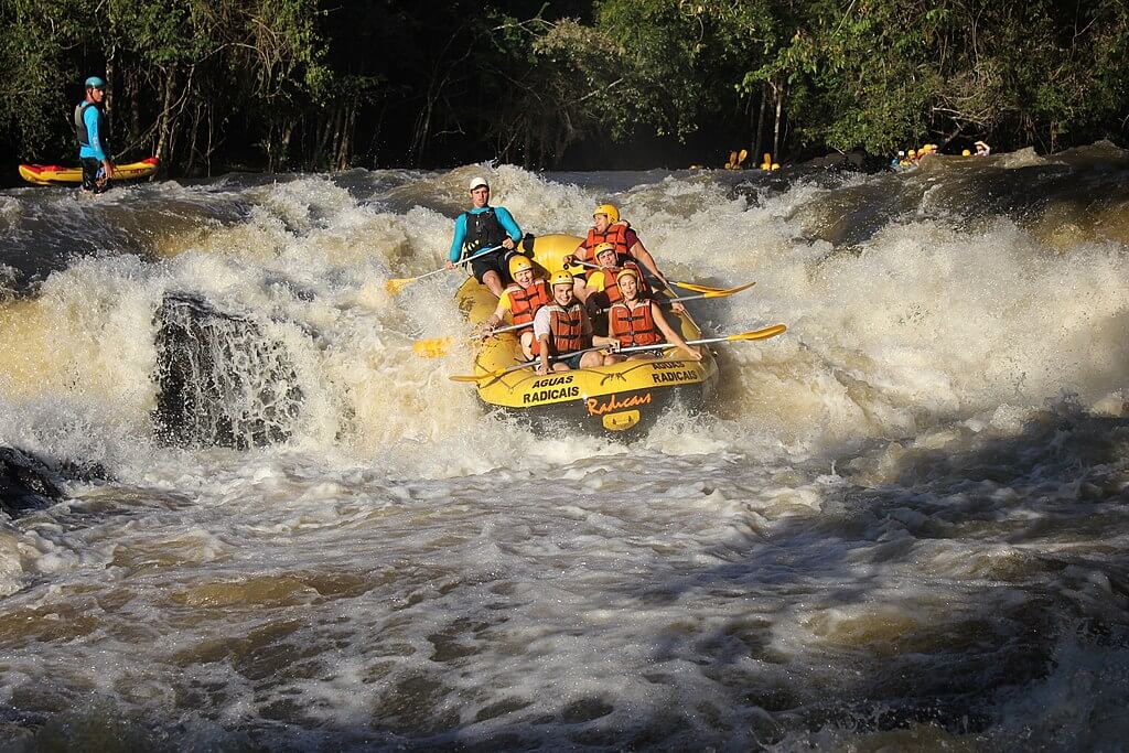Pessoas fazendo turismo de aventura em um rio, com um barco inflável.