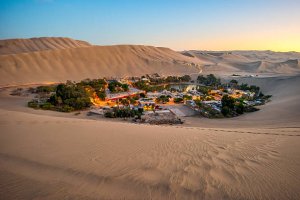 imagem de vilarejo de huacachina em meio ao deserto durante o por do sol