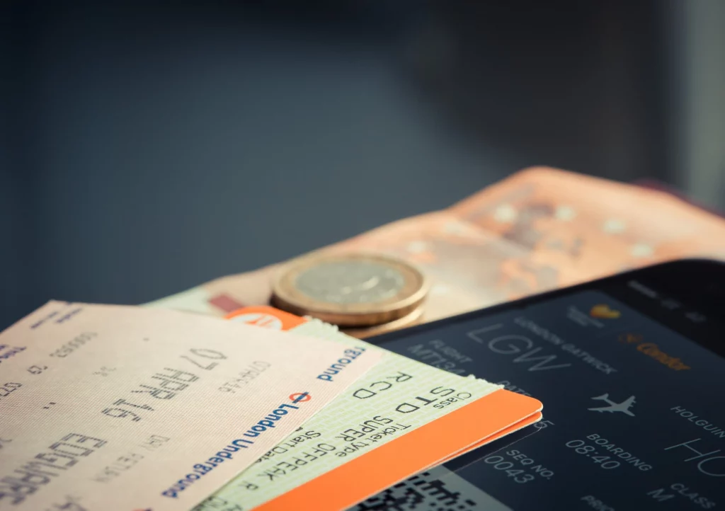 Passagem de avião impressa ao lado de uma moeda. Imagem disponível em Pexels.