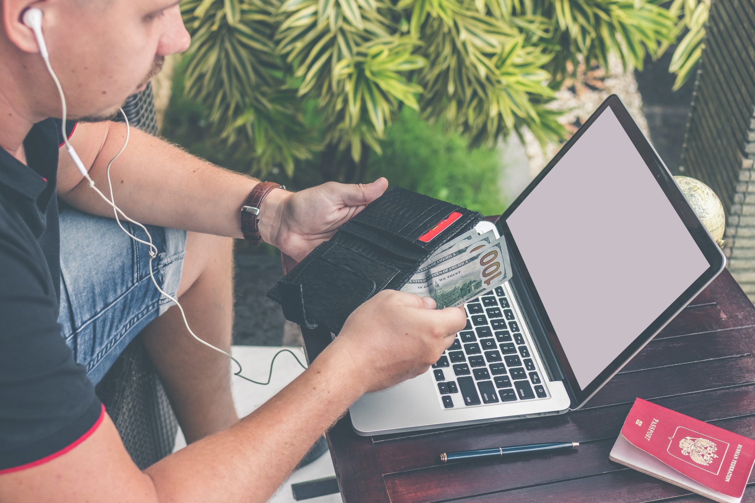 Homem fazendo compra online, com computador na frente e carteira na mão. Imagem disponível no Unsplash