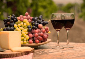 mesa com cachos de uvas e duas taças de vinho tinto