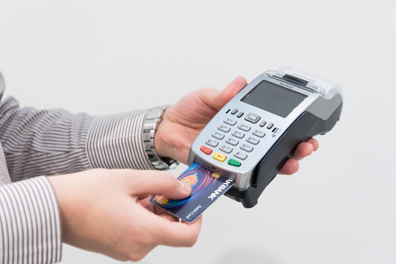Mão de um homem operando máquina de pagamento com cartão de crédito. 