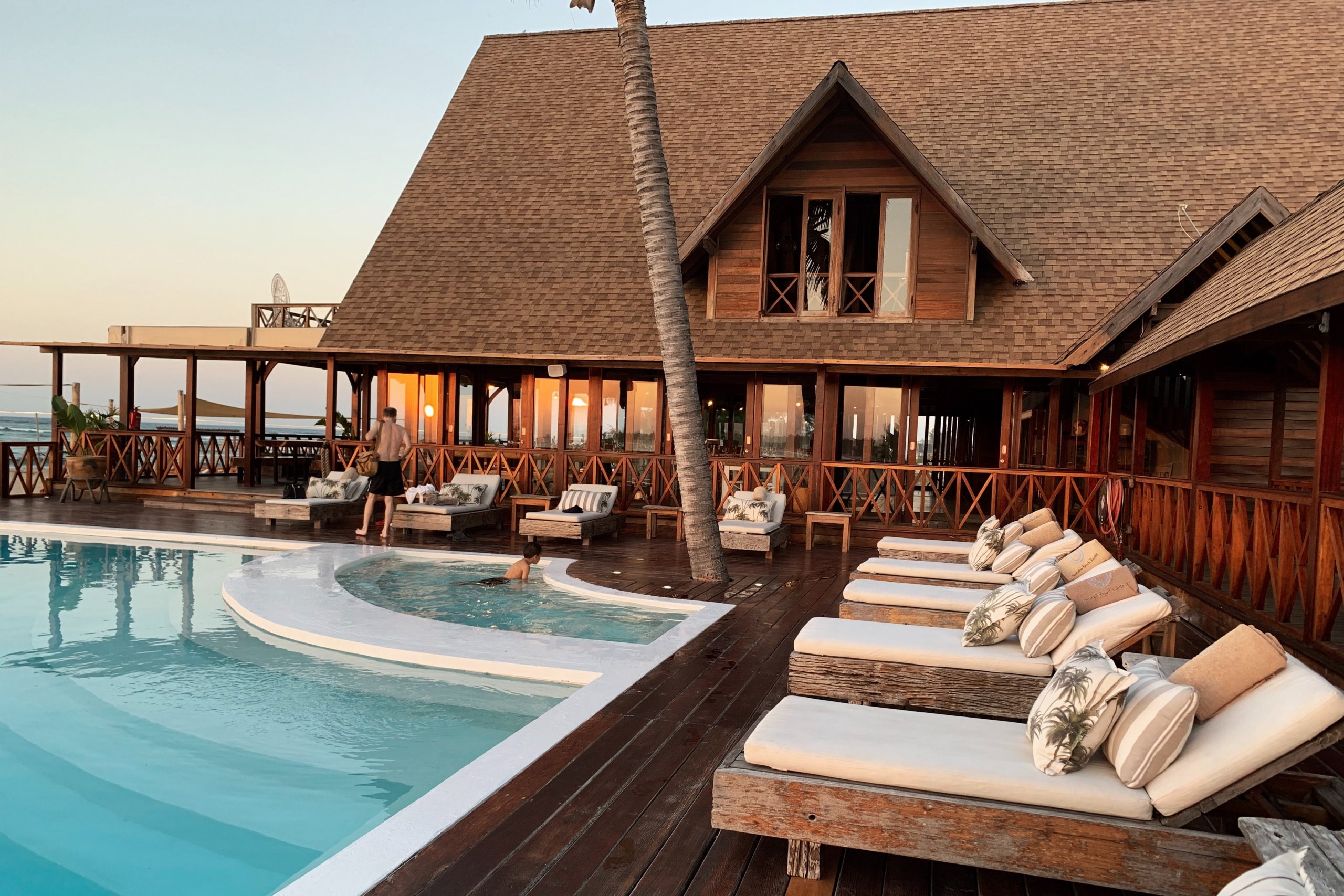 Resort perto da praia, com piscina e casa com estrutura de madeira. Imagem disponível no Unsplash