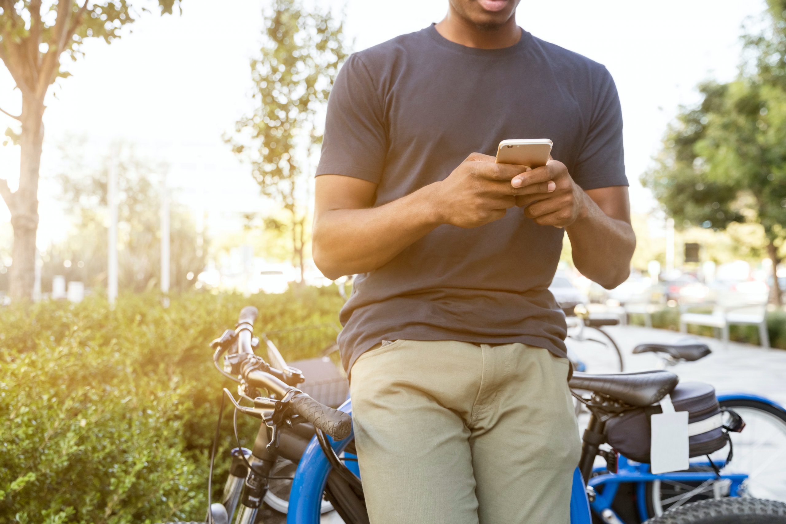 Pessoa Apoiada Em Uma Bicicleta Enquanto Segura Um Smartphone. Imagem disponível no Pexels