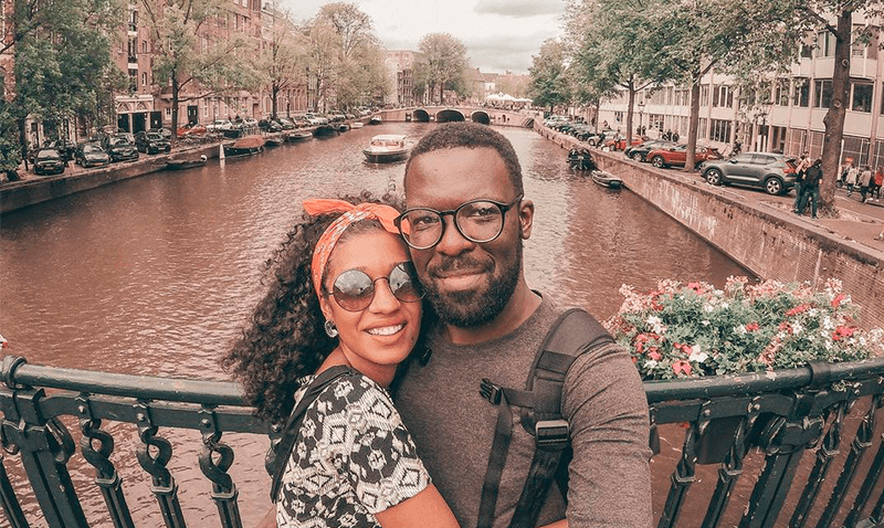 Casal se abraçando em frente a um canal na cidade de Amsterdam