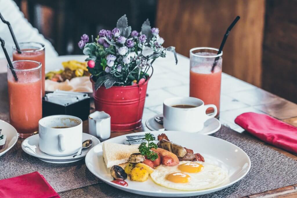 Café da manhã com ovos fritos, suco, café e frutas. Foto disponível no Unsplash