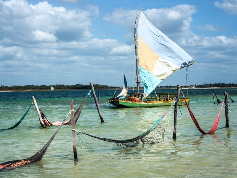 Praia de Jericoacoara com um barco com vela, uma das várias opções de Pacotes de Viagem MaxExperiências