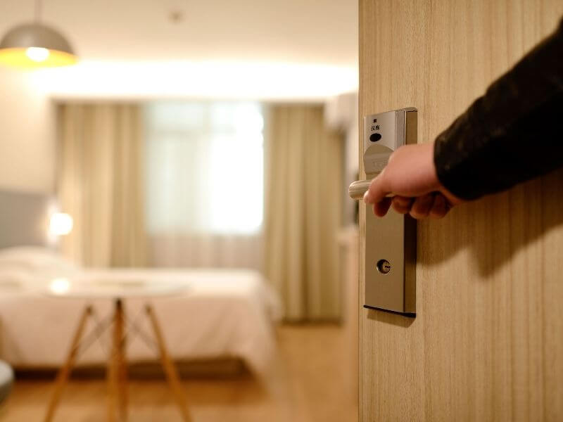 pessoa abrindo a porta do quarto de um hotel, capa do conteúdo sobre hotéis em Fernando de Noronha