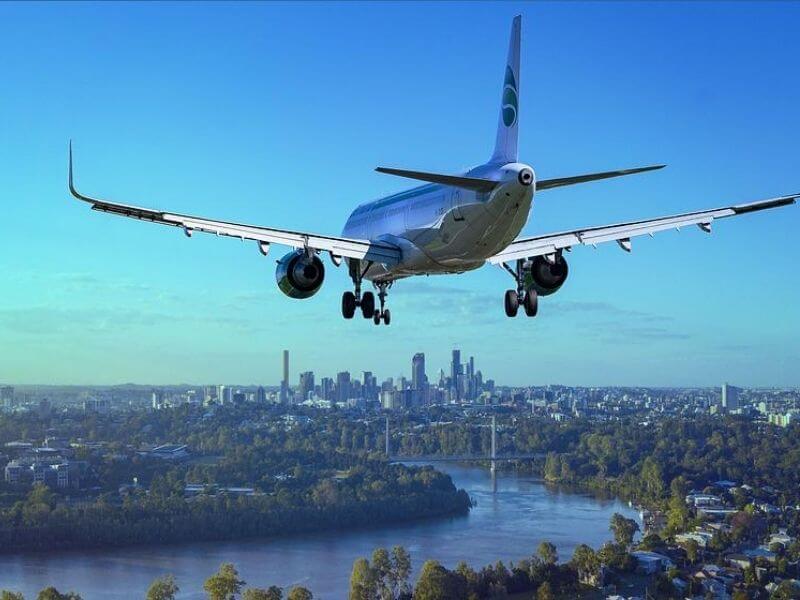 avião fotografado pela parte traseira se aproximando de uma cidade, capa do conteúdo sobre qual a companhia aérea mais barata