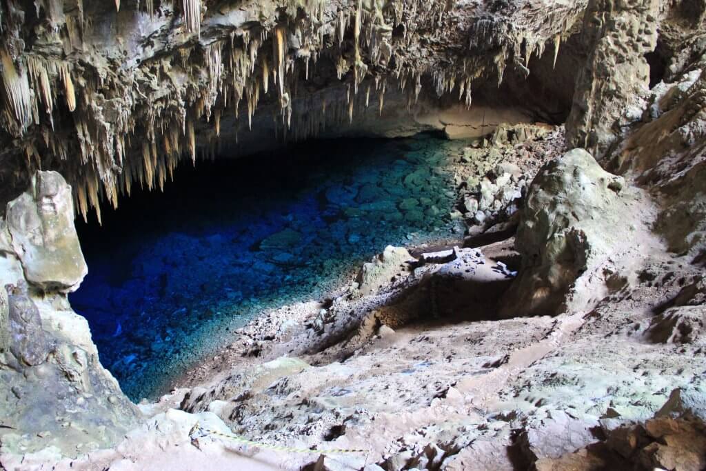 Gruta acinzentada com lago azul. Imagem disponível em Unsplash.