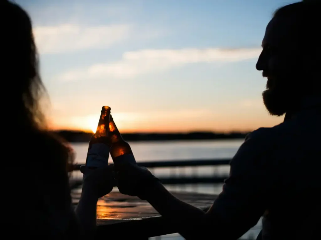 Casal relaxando com uma bebida de frente para a praia representando o que fazer em Porto de Galinhas a noite.