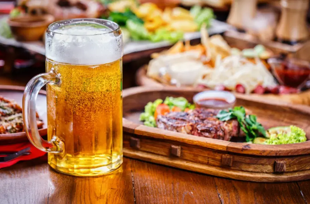 mesa com petiscos de boteco e um caneco cheio de cerveja